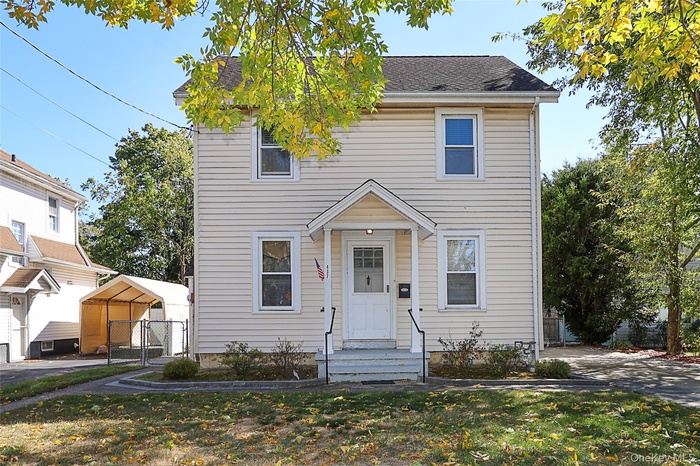 View of front of house featuring roof with shingles, a carport, and a front lawn