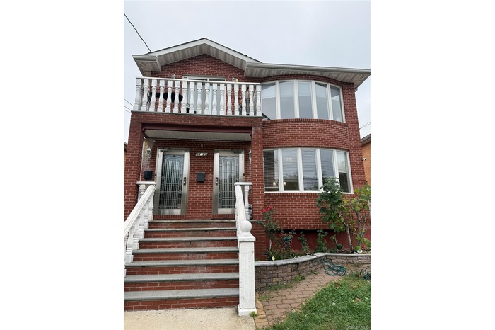 View of front of house featuring brick siding and a balcony