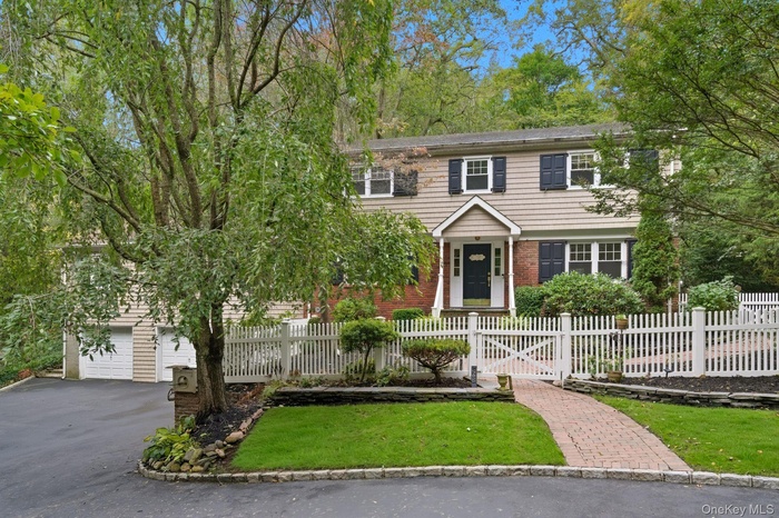 View of front of property with a garage, asphalt driveway, a fenced front yard, and brick siding