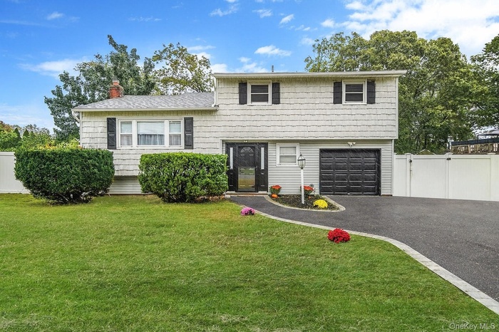 Split level home with driveway, a chimney, and a garage