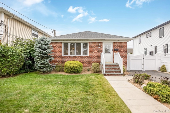 Bungalow-style home with a gate, brick siding, and roof with shingles