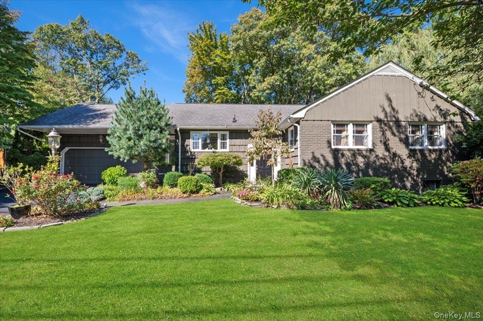 View of front of house with a front lawn, brick siding, and an attached garage