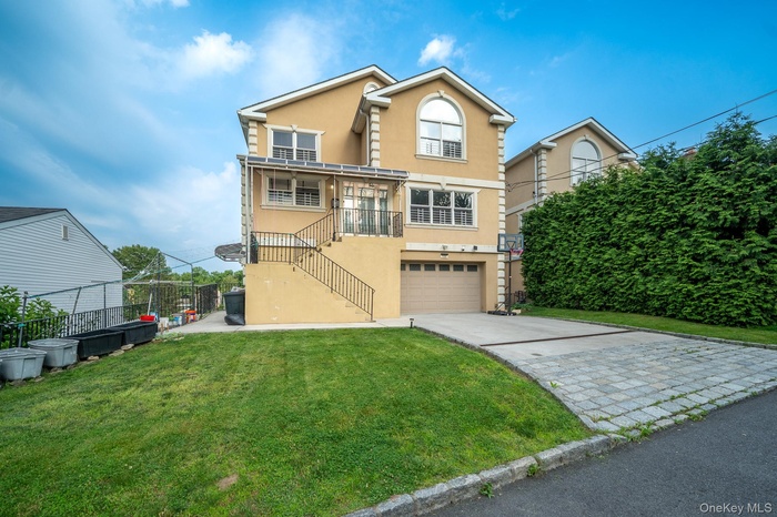 View of front of home featuring stairs, stucco siding, driveway, and a balcony