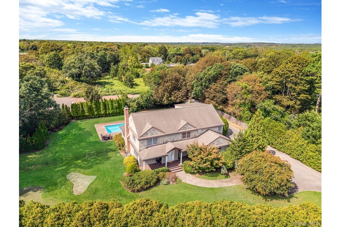 Aerial view of property and surrounding area featuring a forest