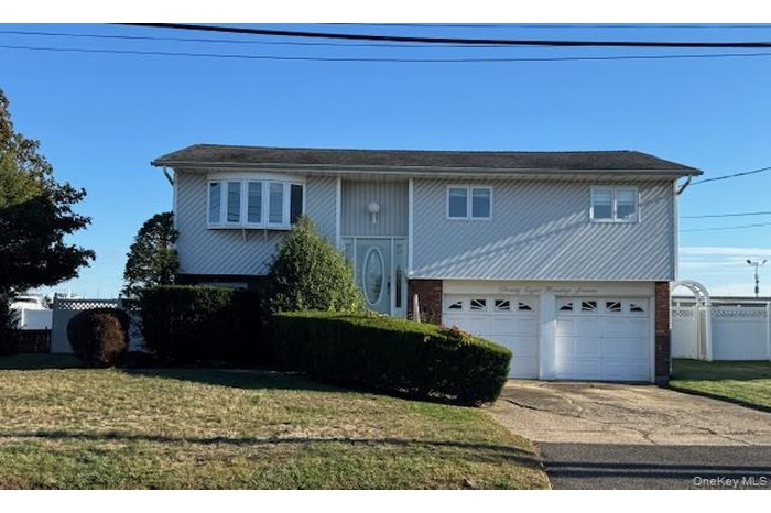 Raised ranch with concrete driveway, a garage, and brick siding