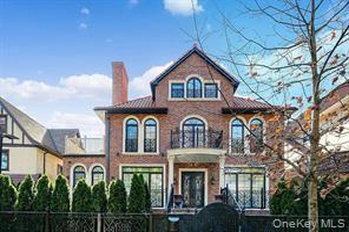 Mediterranean / spanish home featuring a chimney, a fenced front yard, brick siding, and a balcony