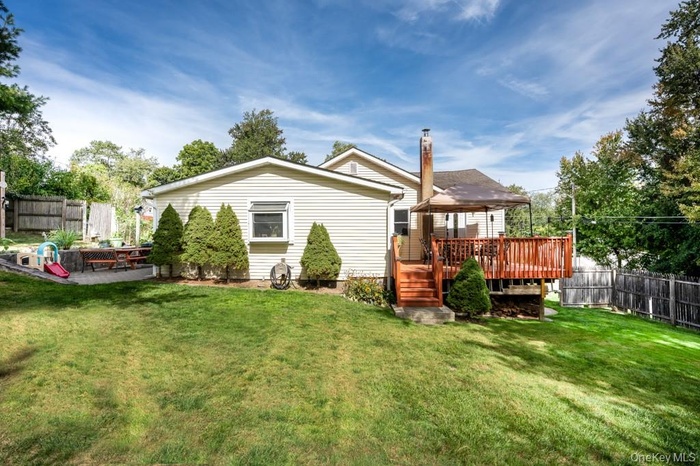 Back of house with a fenced backyard, a deck, and a chimney