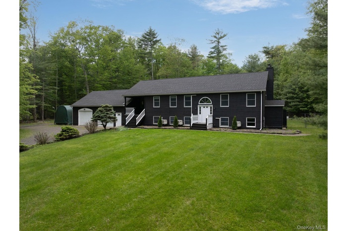 Raised ranch featuring a chimney, gravel driveway, a front lawn, and a garage