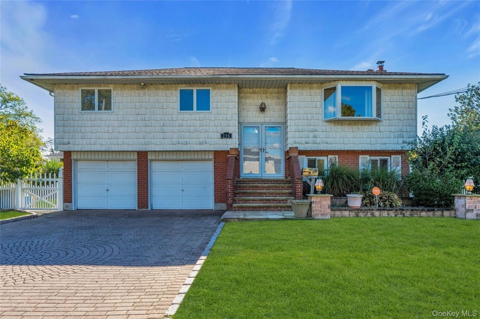 Split foyer home with decorative driveway, an attached garage, and brick siding
