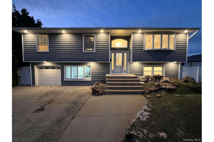 Raised ranch with concrete driveway and an attached garage