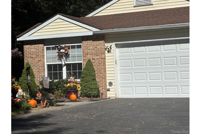 Property entrance with asphalt driveway, brick siding, a shingled roof, and an attached garage