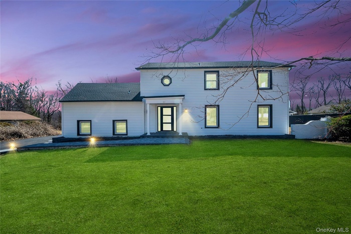 Back of house at dusk with a lawn