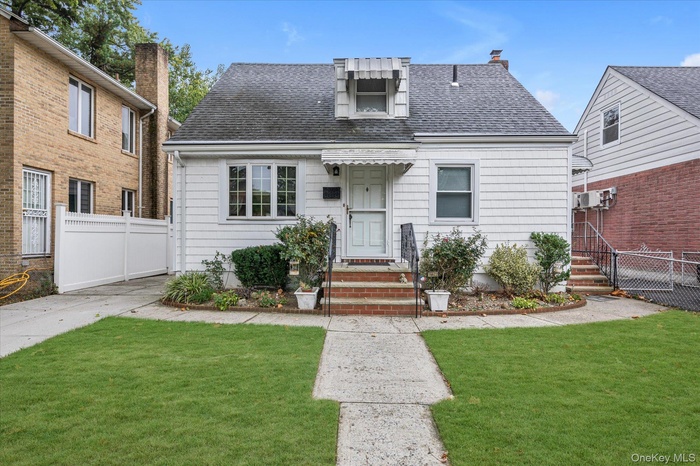 View of front of property featuring a shingled roof and a chimney