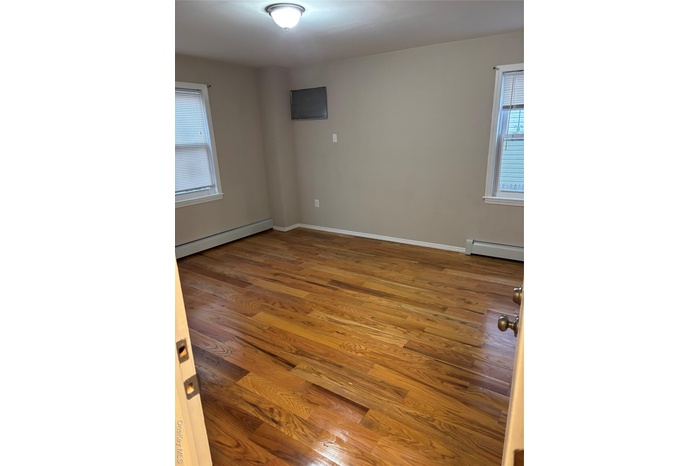 Empty room with a baseboard heating unit and light wood-style flooring