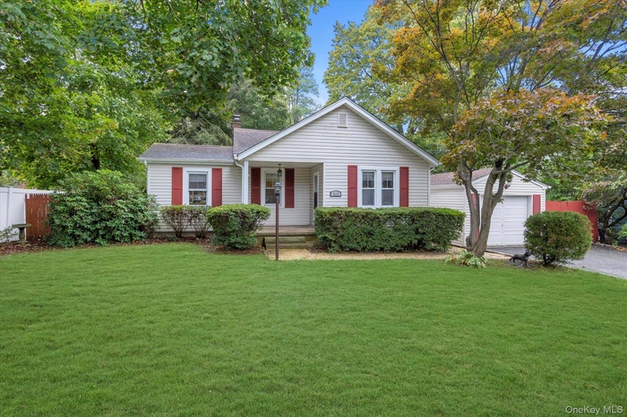 View of front of property with a porch, a garage, and a chimney