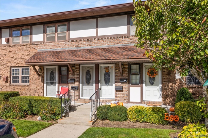 View of front of house featuring brick siding, a shingled roof, and a porch
