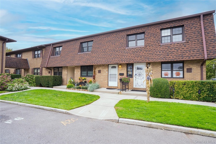 View of front of house with a front lawn, brick siding, and mansard roof