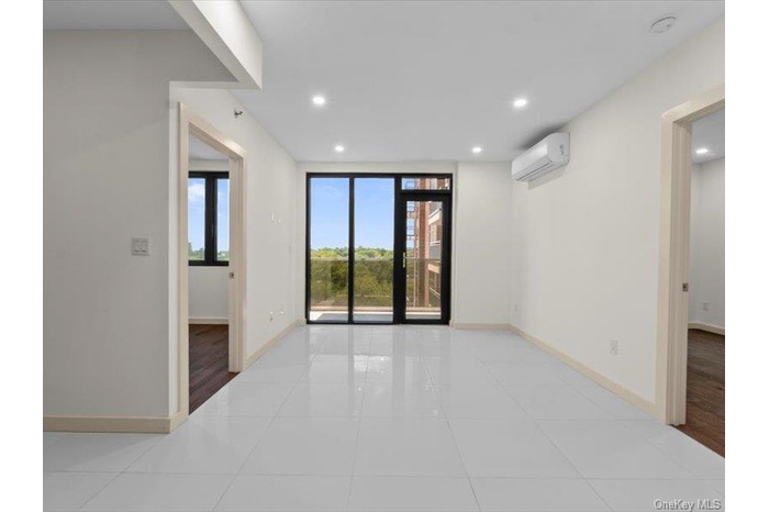Empty room featuring light tile patterned floors, recessed lighting, and a wall unit AC