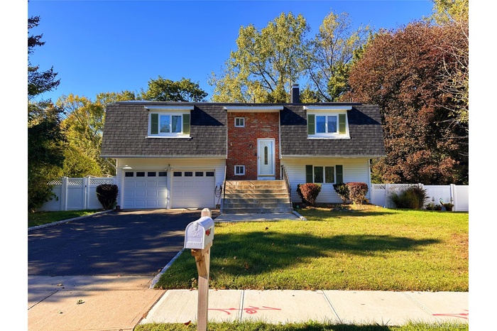 Bi-level home featuring driveway, a gambrel roof, a chimney, and a shingled roof