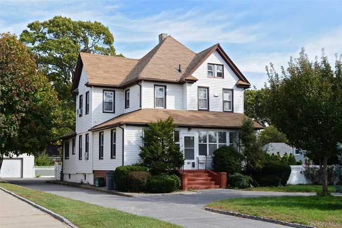 Victorian-style house featuring roof with shingles, a chimney, and a garage