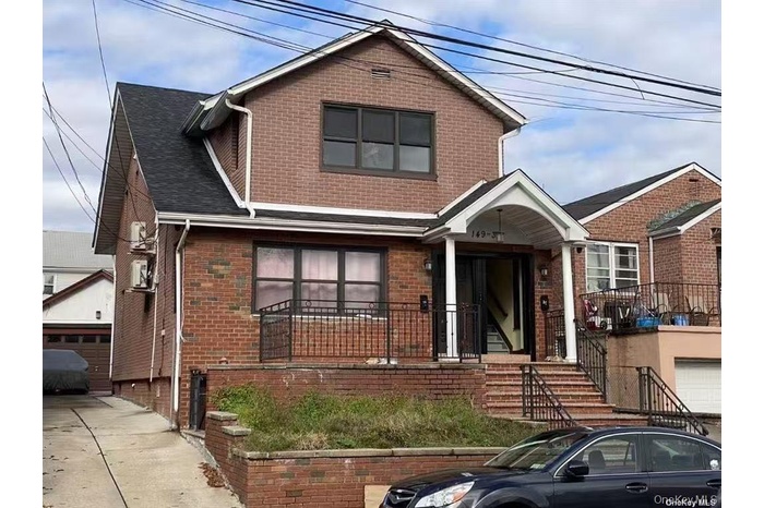View of front of property featuring brick siding, roof with shingles, and a garage