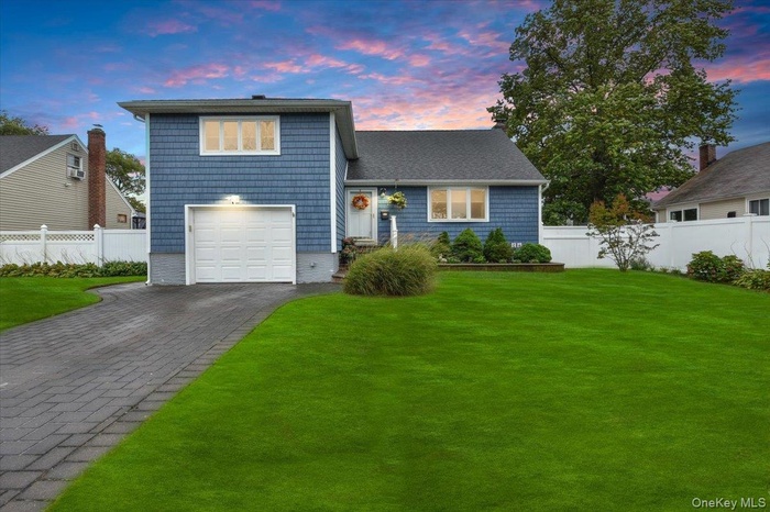 Tri-level home with asphalt driveway, a garage, and roof with shingles