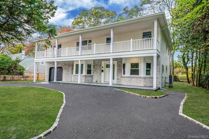 View of front of property featuring a porch, brick siding, and asphalt driveway