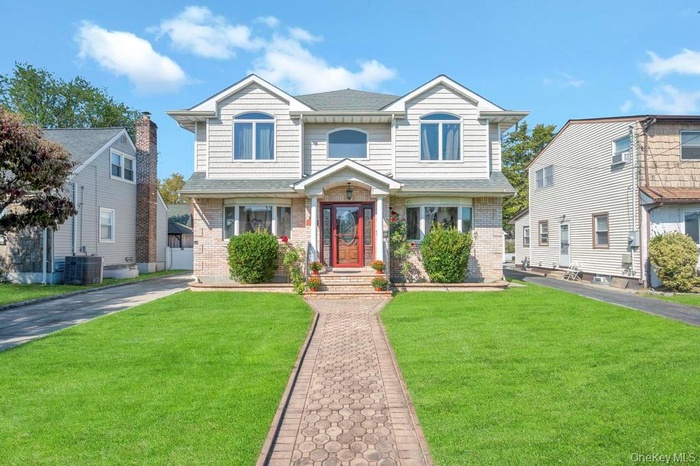 View of front of house featuring brick siding, roof with shingles, and a front lawn