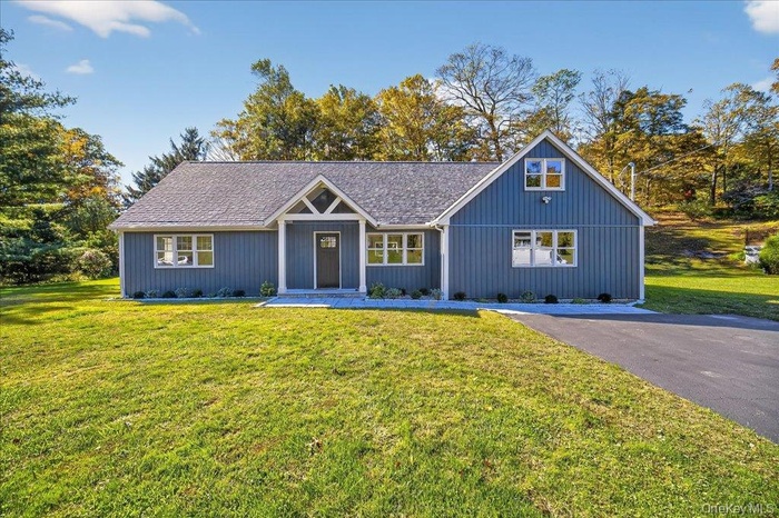 View of front of house with a front lawn and roof with shingles