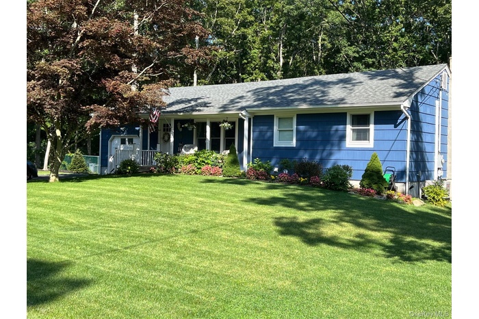 Ranch-style house featuring a front yard, a porch, and a shingled roof