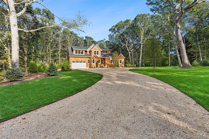 Front of home featuring driveway, front lawn, cedar siding, and an attached garage