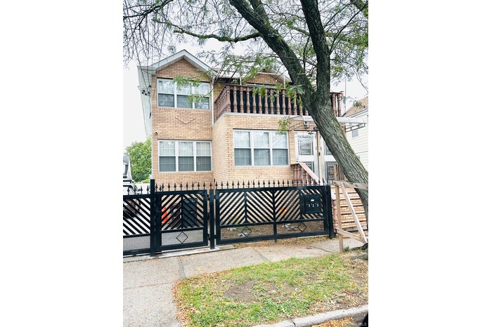 View of front of home with brick siding, a fenced front yard, and a gate