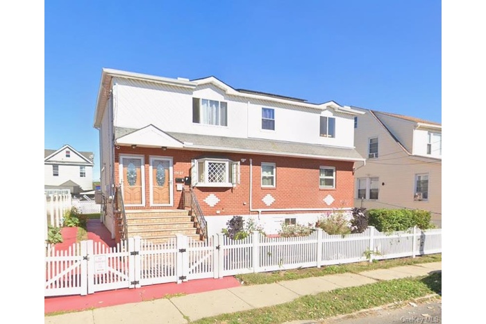 View of front of house with a gate, a fenced front yard, and brick siding
