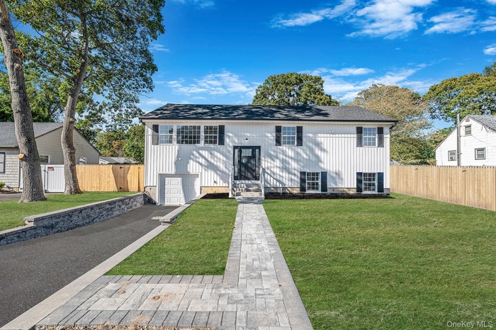 Split foyer home with a shingled roof, entry steps, and asphalt driveway