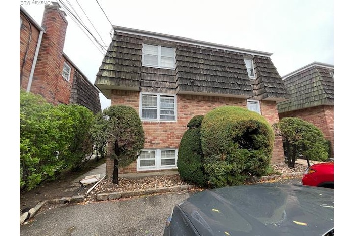 View of front of property with mansard roof and brick siding