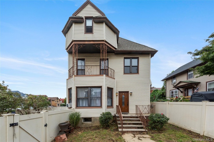 Victorian-style house with a gate, a fenced backyard, a balcony, a shingled roof, and cooling unit