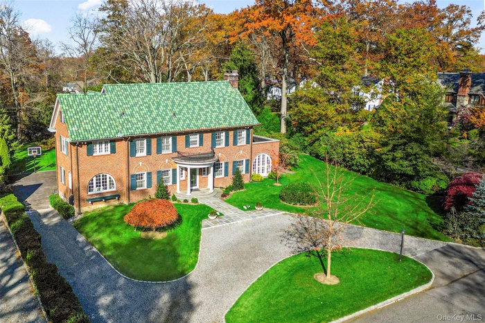 Colonial inspired home featuring a chimney, a front yard, and brick siding