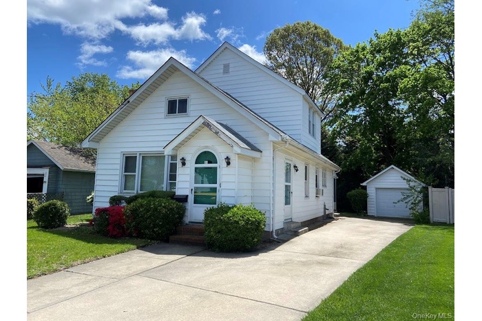 Bungalow-style house with an outdoor structure, a front yard, a garage, and driveway