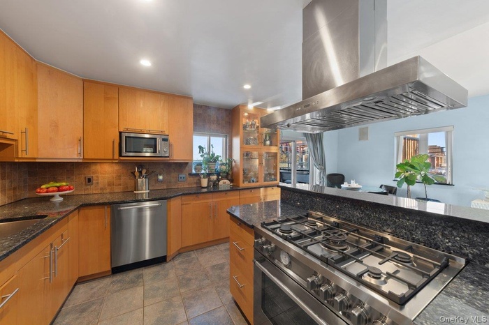 Kitchen , dark granite counter top, appliances with stainless steel finishes, decorative backsplash, and recessed lighting