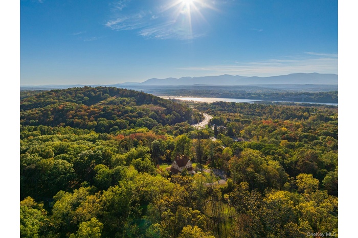 View of mountain backdrop featuring a nearby body of water and a forest