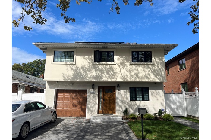 Colonial house with a garage, stucco siding, and driveway