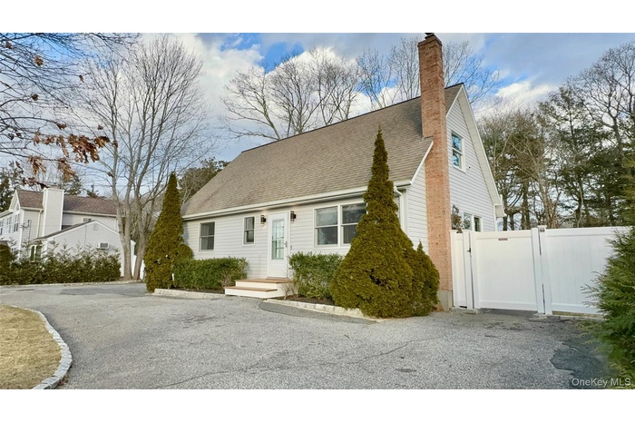 Cape cod home with a chimney, a gate, fence, and roof with shingles