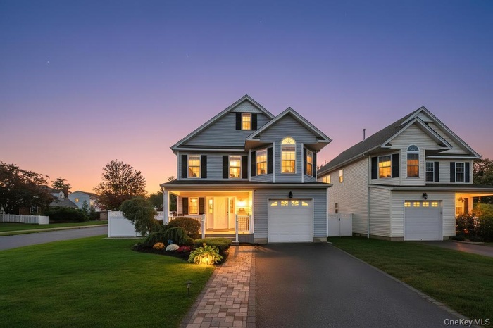 Traditional-style house with a lawn, a porch, driveway, and a garage