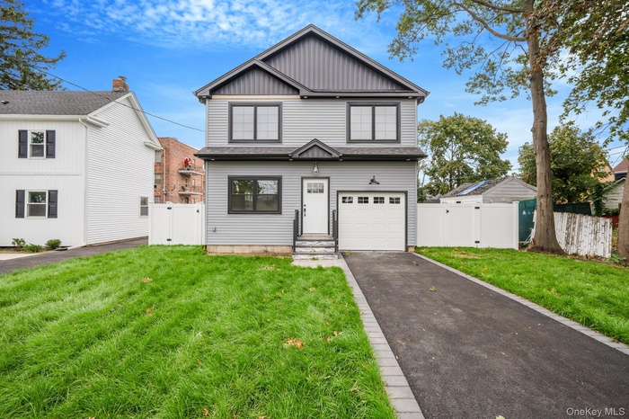 View of front of house with a gate, asphalt driveway, board and batten siding, and an attached garage