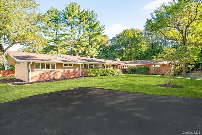 Single story home featuring brick siding, a front yard, and a chimney