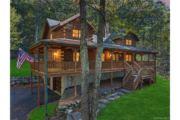 Log home with a large porch, asphalt driveway, a front yard, and an attached garage