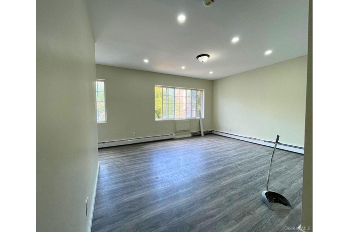 Empty room featuring wood finished floors, recessed lighting, and a baseboard heating unit