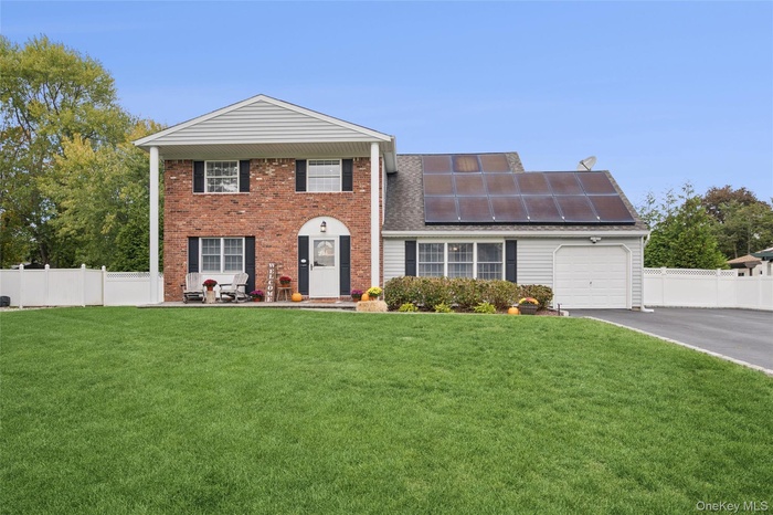 View of front of home with roof mounted solar panels, a garage, asphalt driveway, and brick siding