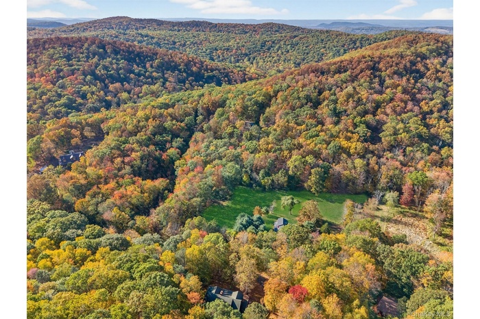 Aerial view of property and surrounding area with a heavily wooded area