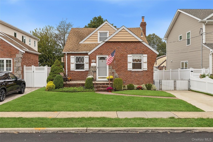 View of front of home with brick siding, a gate, a chimney, and roof with shingles